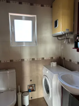 Small bathroom equipped with sanitary fixtures, a washing machine, and a yellow water heater. - image 12