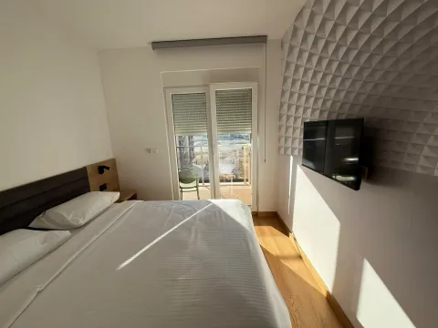 Moderna spavaća soba sa bračnim krevetom, TV-om i izlazom na terasu. - image 9