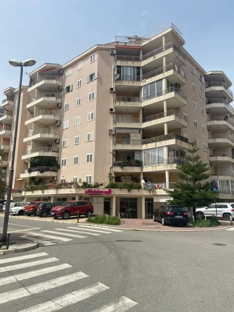 View of the facade and entrance of an apartment building with terraces.
