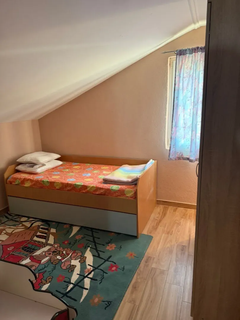 Children's bedroom with a bed and wardrobe under a sloping ceiling.