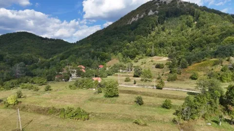 Pogled na seoski predio sa zelenim brdima i kućama u pozadini. - image 3