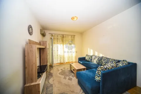 Living room with a blue sectional sofa, wooden furniture, and a rug. - image 2