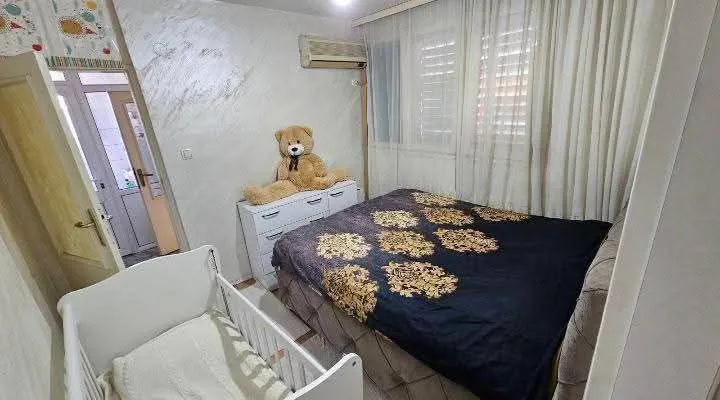 Namještena spavaća soba sa bračnim krevetom i krevetcem.
