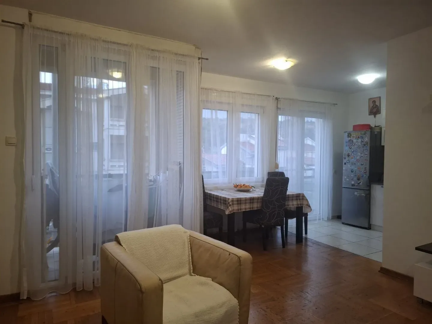 Svijetla dnevna soba sa trpezarijskim stolom i foteljom u prvom planu.
