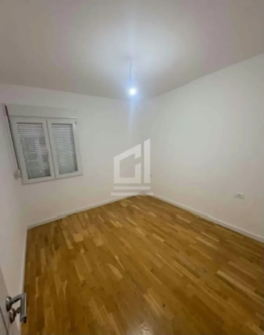 Prazna soba sa bijelim zidovima i drvenim podom.