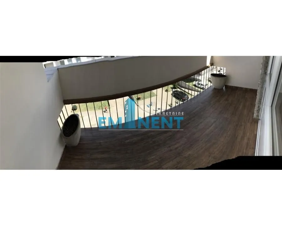 Spacious balcony with wooden flooring and a view of the surroundings.