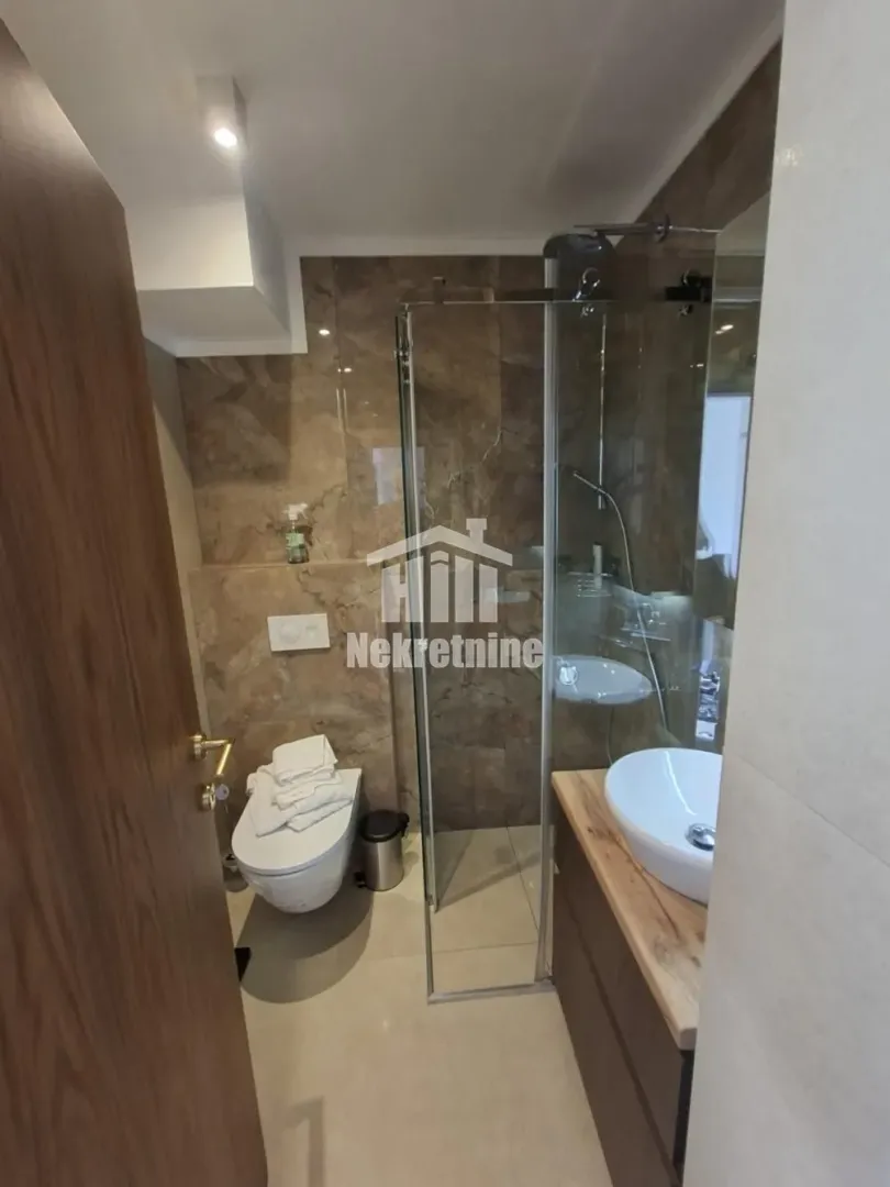 Modern bathroom with a walk-in shower, washbasin, and toilet.