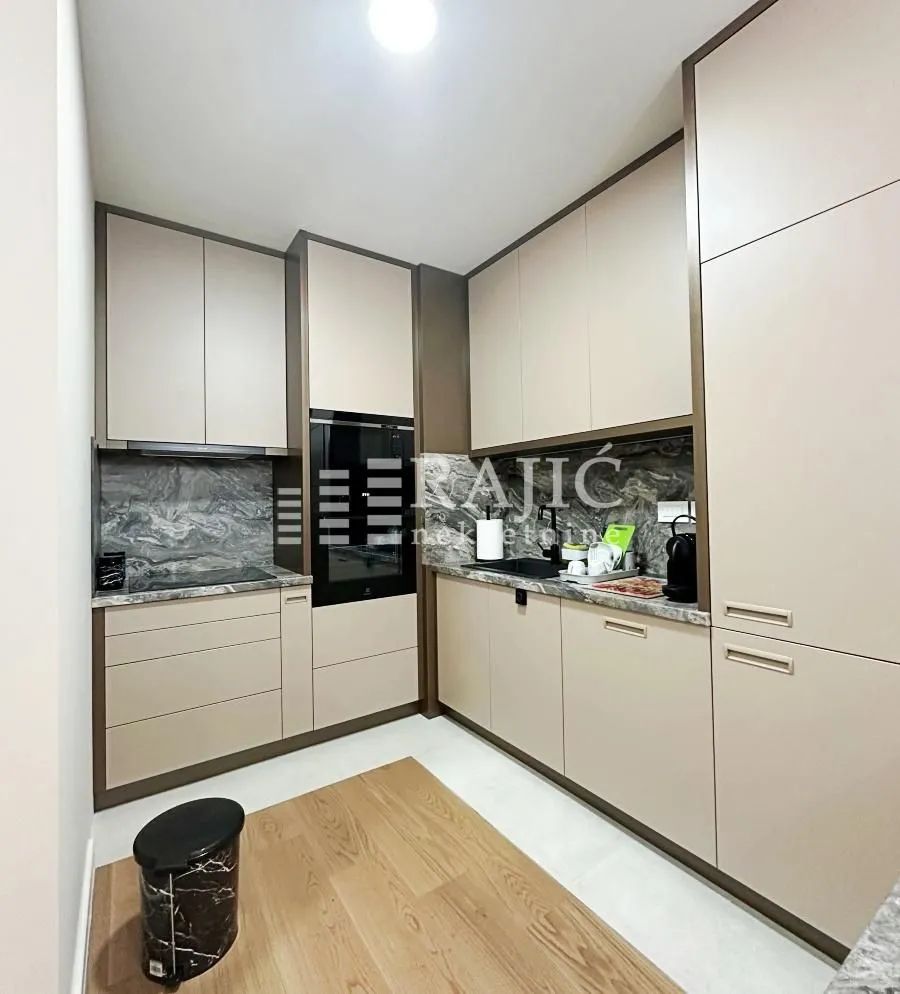 Modern kitchen with beige cabinets and marble backsplash.