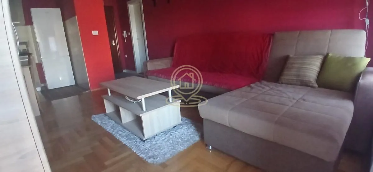 Living room with a sectional sofa, coffee table, and red accent wall.
