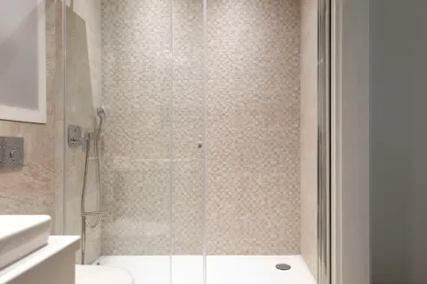Modern walk-in shower with a glass screen and mosaic tiles in the bathroom. - image 9