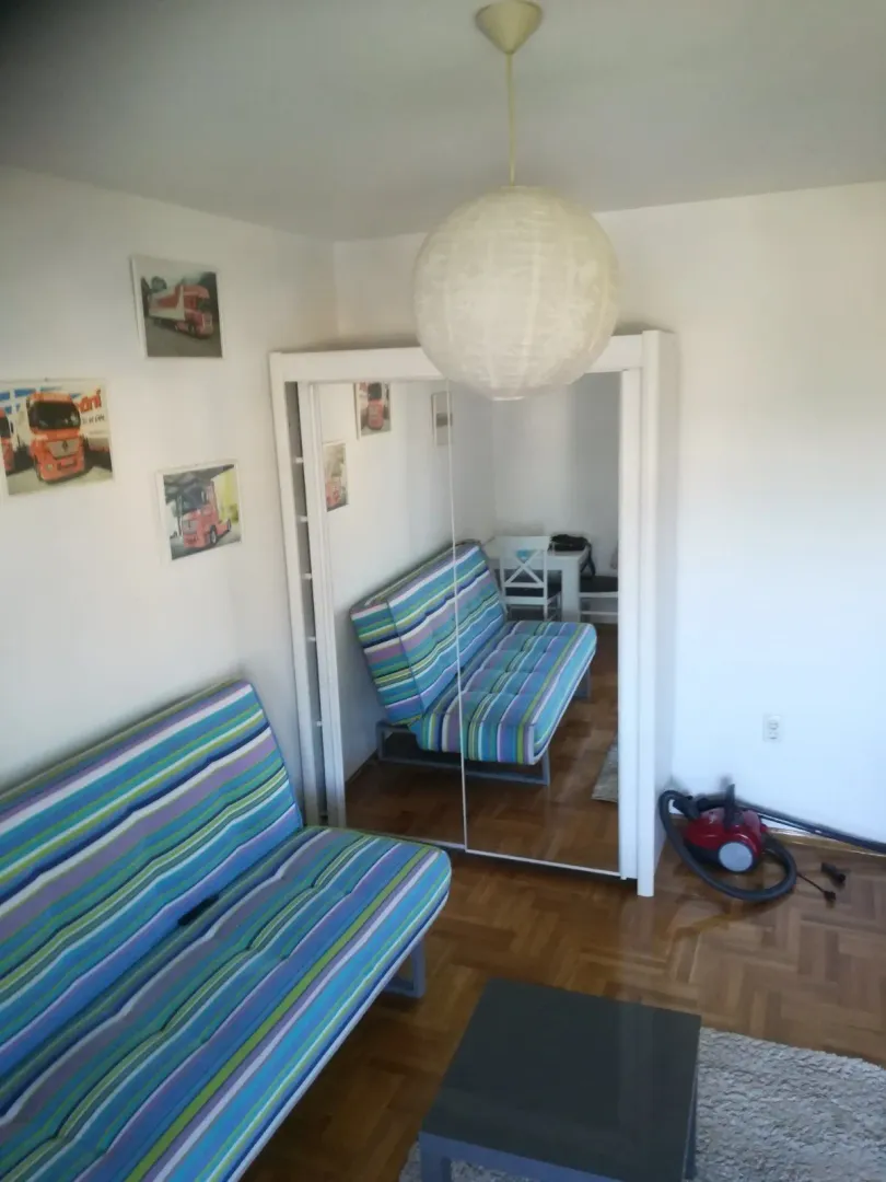 Soba sa šarenim kaučem na pruge i ormarom sa ogledalima.