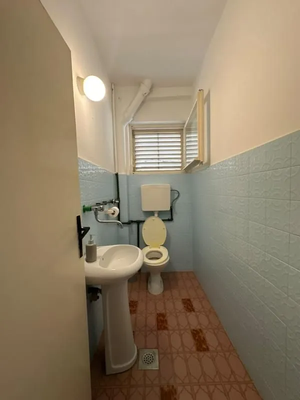 Manje kupatilo sa umivaonikom, WC šoljom i plavim pločicama.