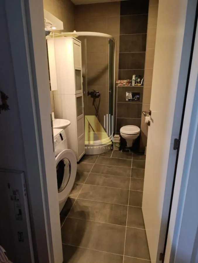 View of the bathroom with a shower cabin, toilet, and washing machine.