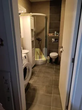 View of the bathroom with a shower cabin, toilet, and washing machine. - image 8