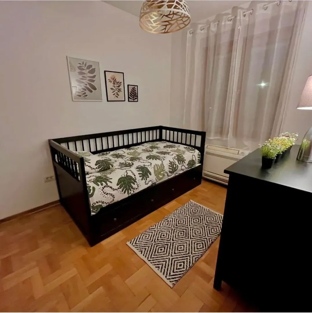 Children's bedroom with a bed, dresser, and parquet flooring.