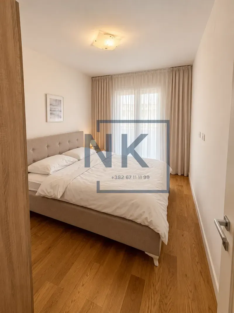 Furnished bedroom with a double bed and wooden flooring.