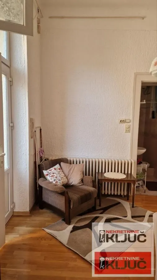 Manji dnevni boravak sa foteljom, stočićem i parketom na podu.