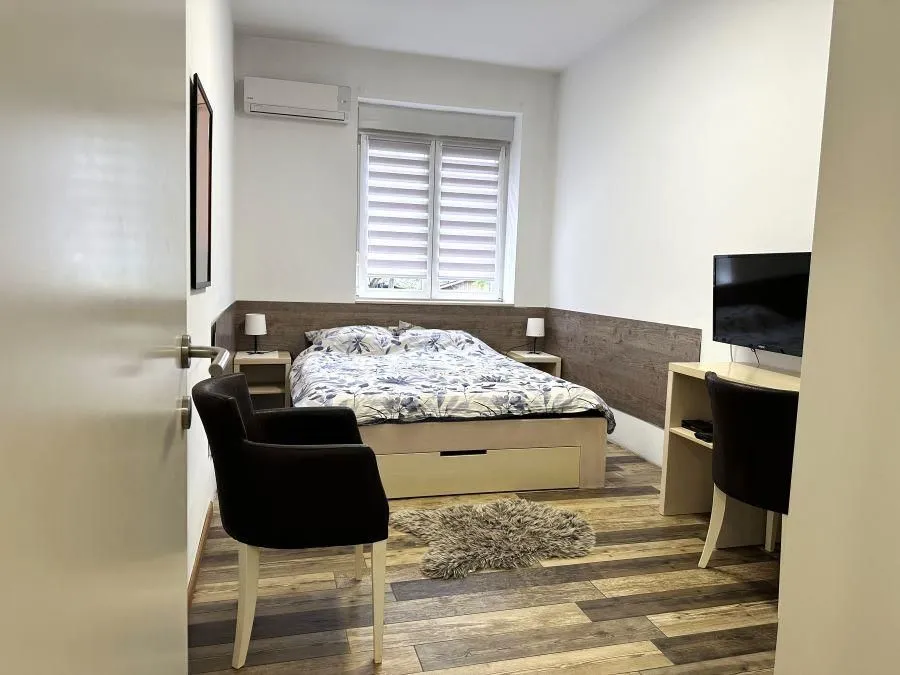 Furnished bedroom with a double bed, desk, and television.