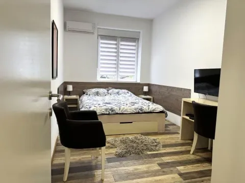 Furnished bedroom with a double bed, desk, and television. - image 5