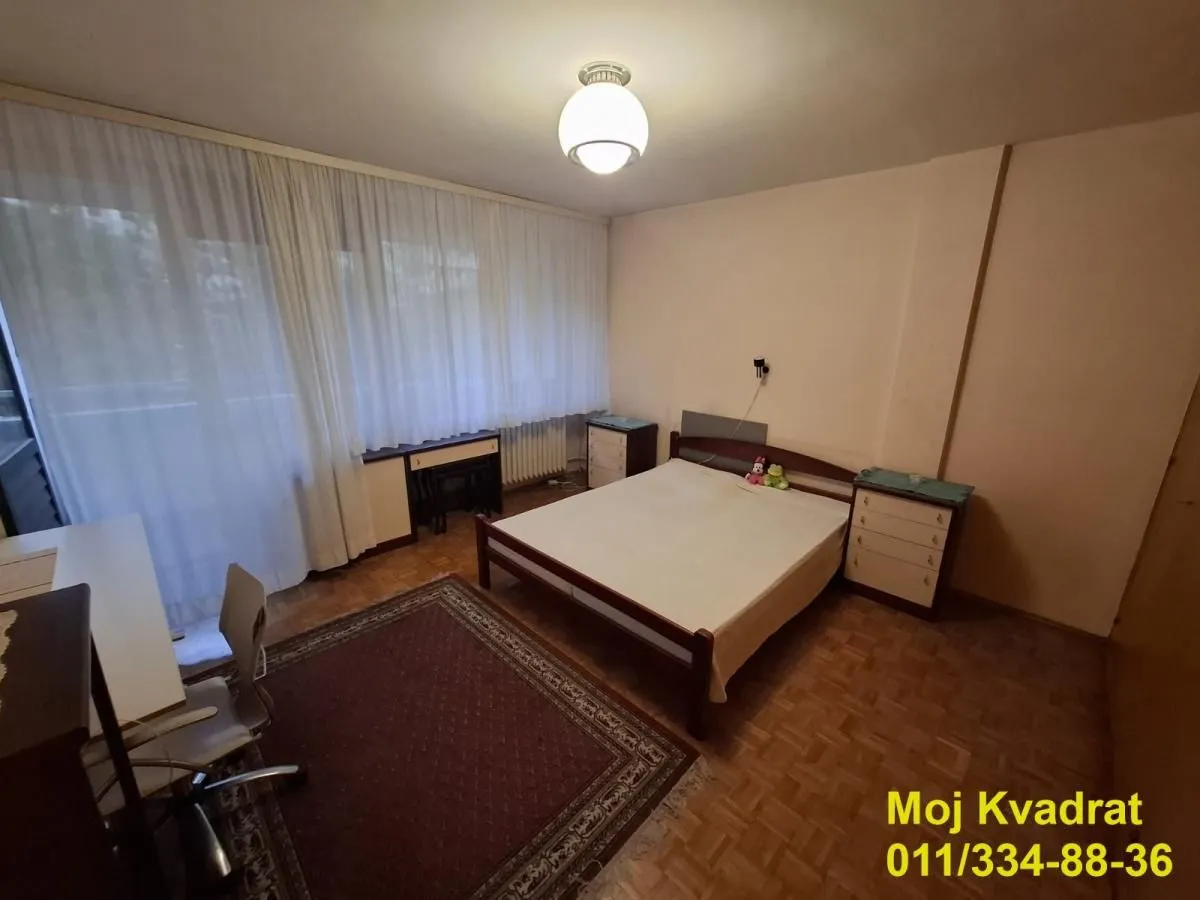Spavaća soba sa bračnim krevetom, radnim stolom i tepihom.