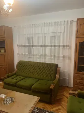 Living room with a green sofa and wooden furniture. - image 16