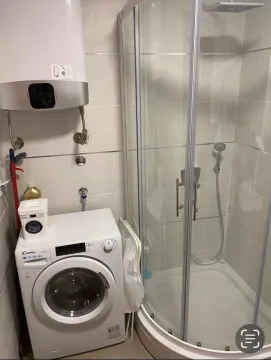 Small bathroom with a shower cabin, washing machine, and water heater. - image 14