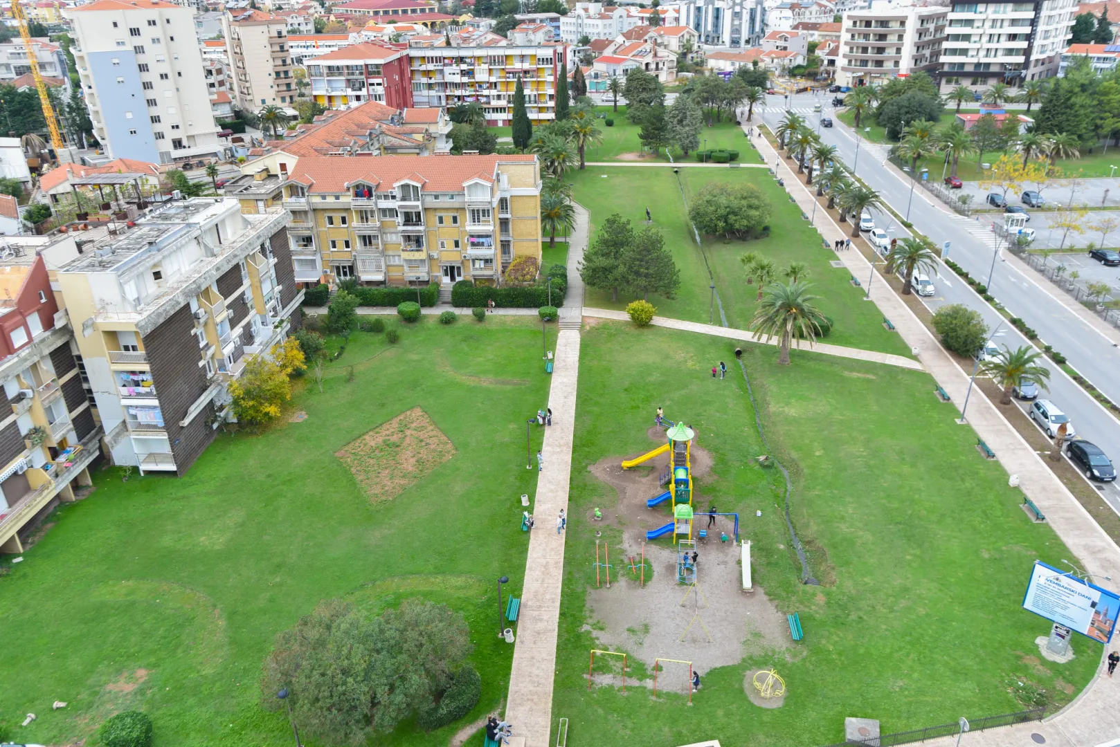 View from the terrace overlooking a landscaped park, green areas, and the urban surroundings.