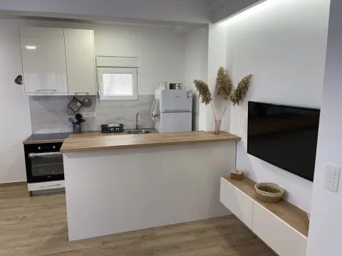 Svijetla i moderna kuhinja sa šankom i televizorom na zidu. - image 2
