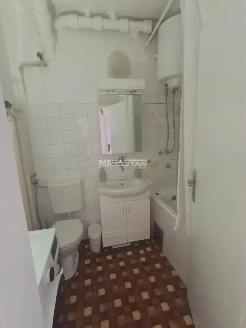 Small bathroom with a bathtub, washbasin, toilet, and water heater.