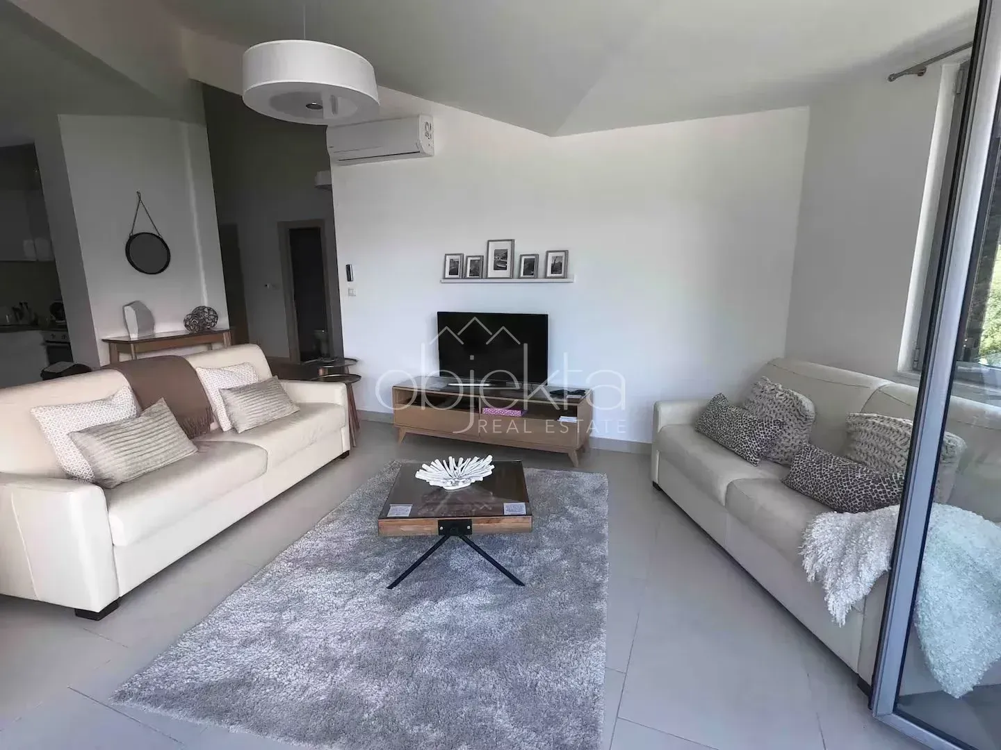 Living room with sofas, a TV, and access to the terrace.