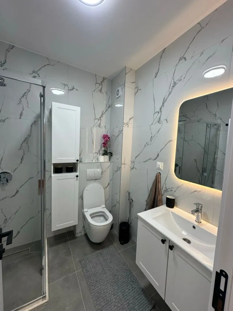 Moderne kupatilo sa tuš kabinom, umivaonikom i wc šoljom.