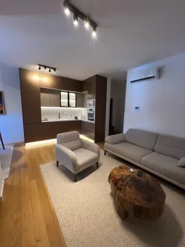 Living room with a sofa set and a built-in kitchen in the background. - image 13