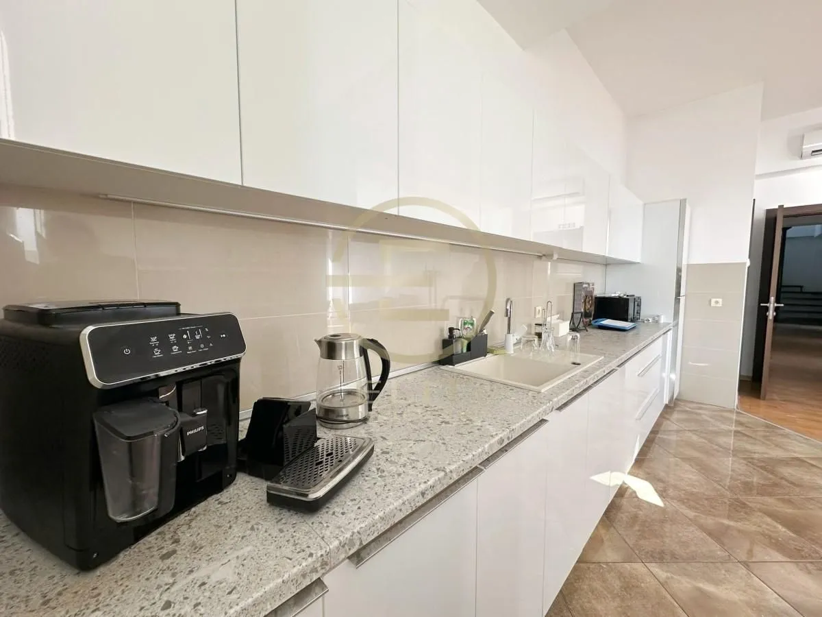 View of white kitchen cabinets and countertops with appliances.
