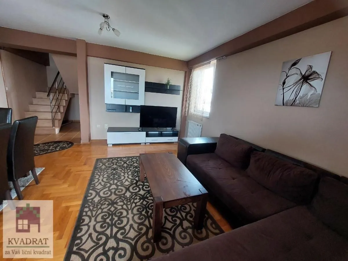 Living room with a sofa, TV unit, and stairs in the background.