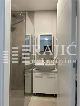 View of a modernly decorated bathroom with a walk-in shower and a sink vanity. - image 9