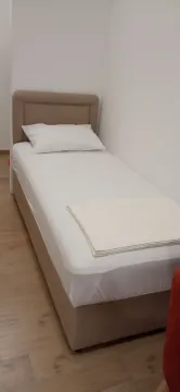 Single bed with white bedding in a bedroom. - image 6