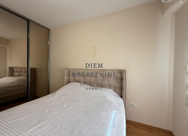 Furnished bedroom with a double bed and a mirrored built-in wardrobe.