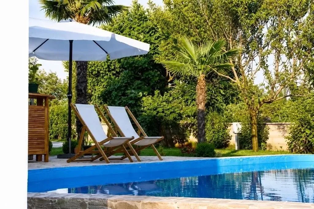 Yard with a swimming pool, sun loungers, and an umbrella.