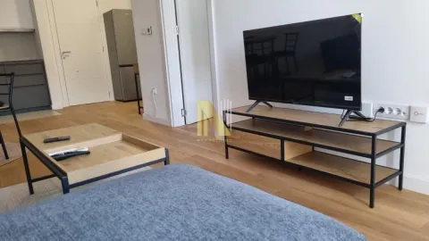 Dnevna soba sa televizorom, stočićem i sofom, sa pogledom na kuhinju. - image 3