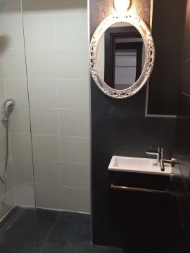 Modern bathroom featuring a shower cabin, small sink, and an ornate oval mirror. - image 9