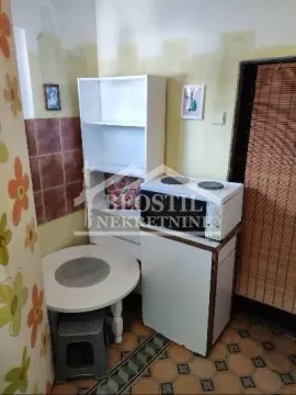Small kitchen with a stove, refrigerator, table, and shelving units. - image 8