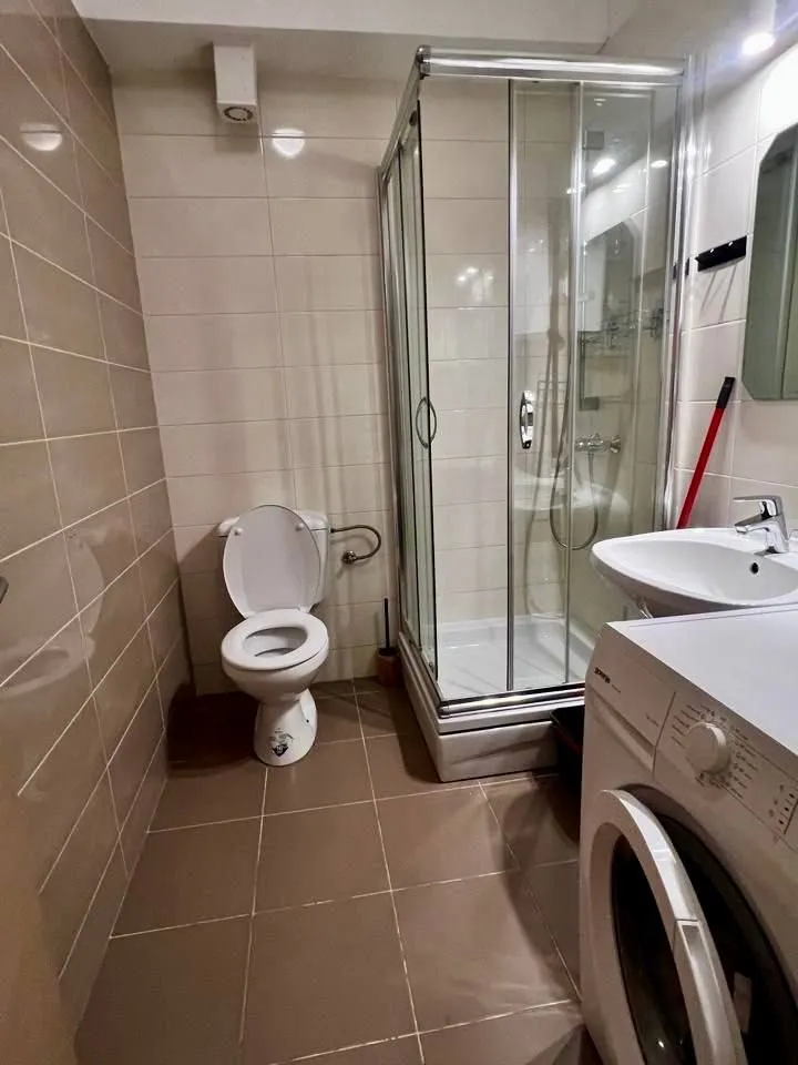 Manje kupatilo sa tuš kabinom, umivaonikom i veš mašinom.