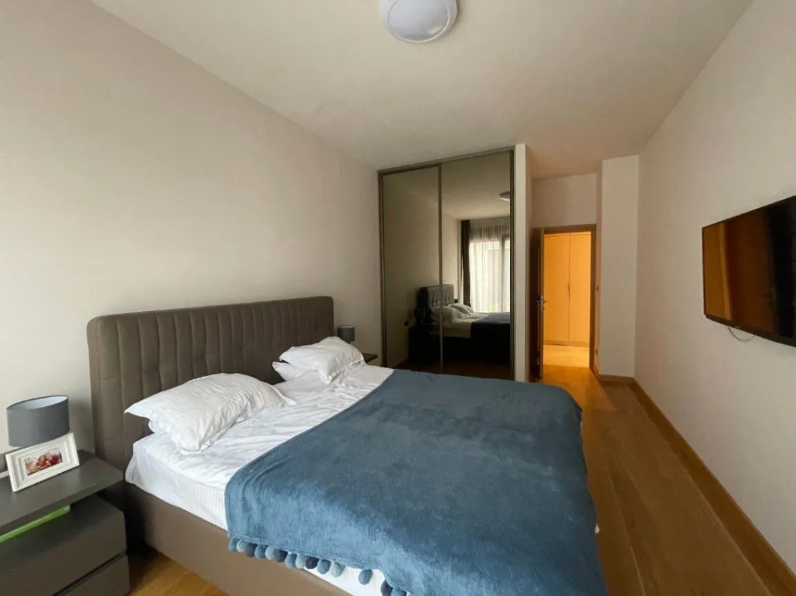 Bright bedroom featuring a double bed, a built-in wardrobe, and a wall-mounted TV.