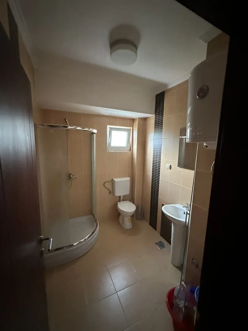Jednostavno kupatilo sa tuš kabinom, lavaboom i bojlerom.