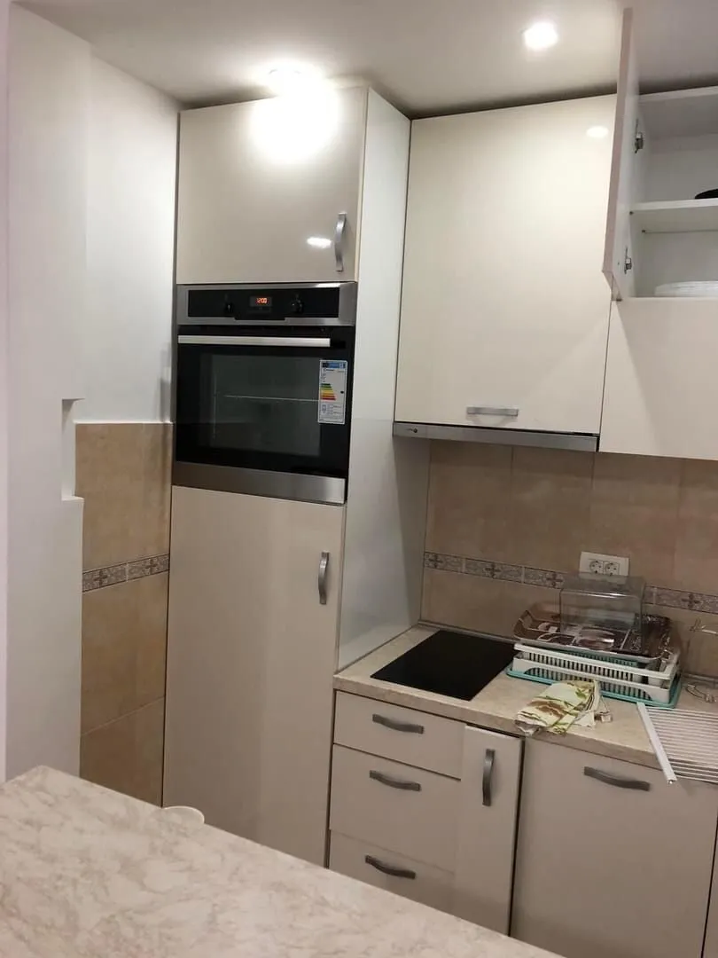 Smaller kitchen with light-colored cabinets and a built-in oven.