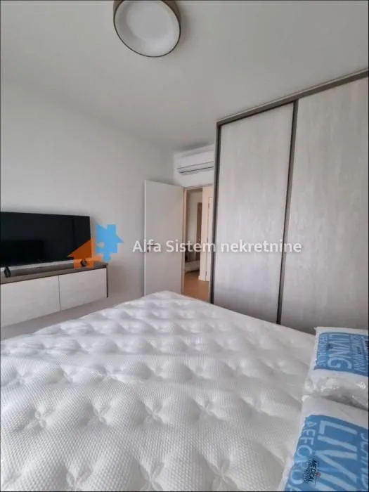 Furnished bedroom with a double bed, wardrobe, and television.