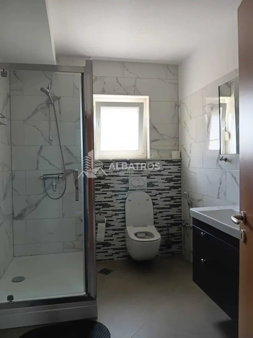 Modernly equipped bathroom with a walk-in shower, washbasin, and toilet.