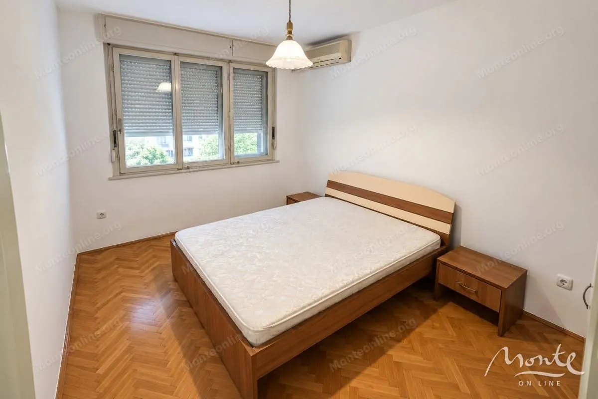 Spavaća soba sa bračnim krevetom i drvenim podom.