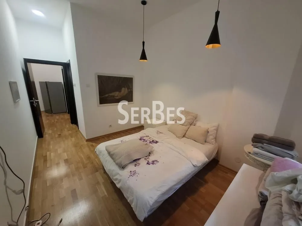 Furnished bedroom with a double bed and wooden flooring.