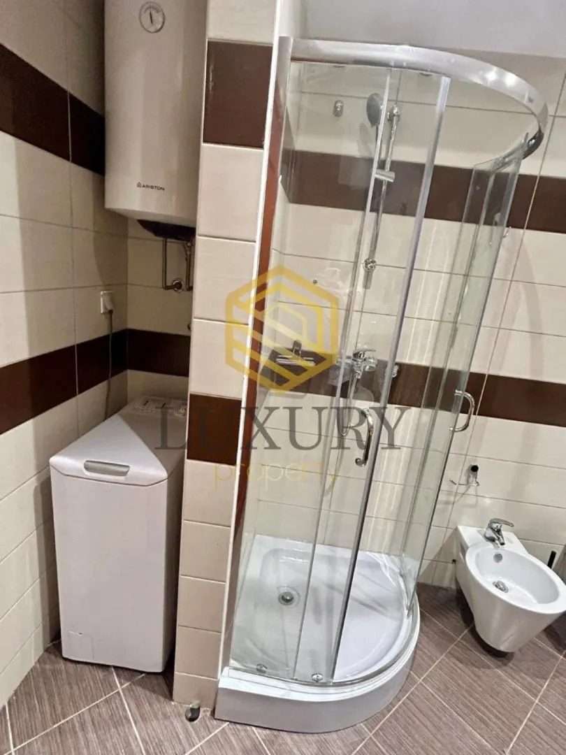 Manje kupatilo sa tuš kabinom, bideom, veš mašinom i bojlerom.